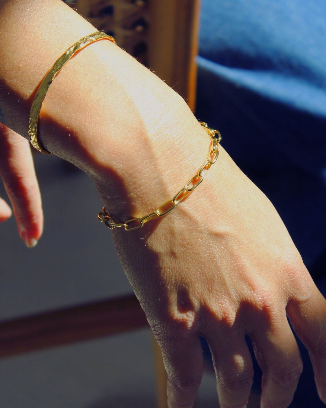Fine link Gold chain bracelet on a wrist with a blurred background