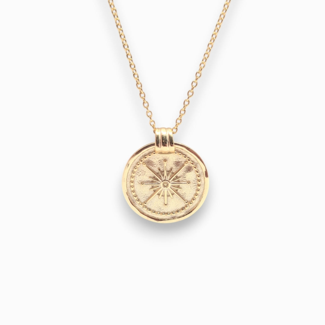 Gold necklace with a round pendant on a white background