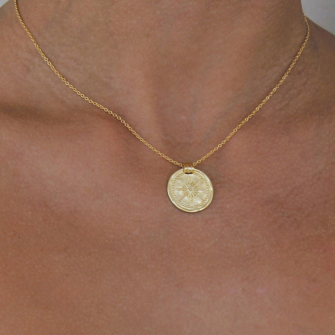 18 carat Gold necklace with a round pendant on a person's neck against a neutral background