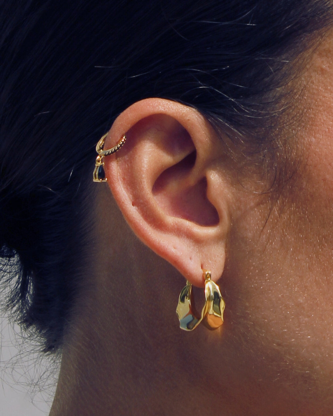 Close-up of an ear wearing gold hoop earrings including the Bronte Pendant hoops.