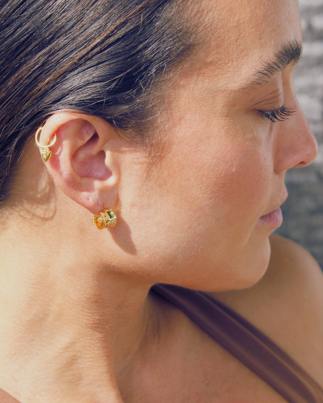Close-up of a woman wearing gold hoop earrings with a blurred background