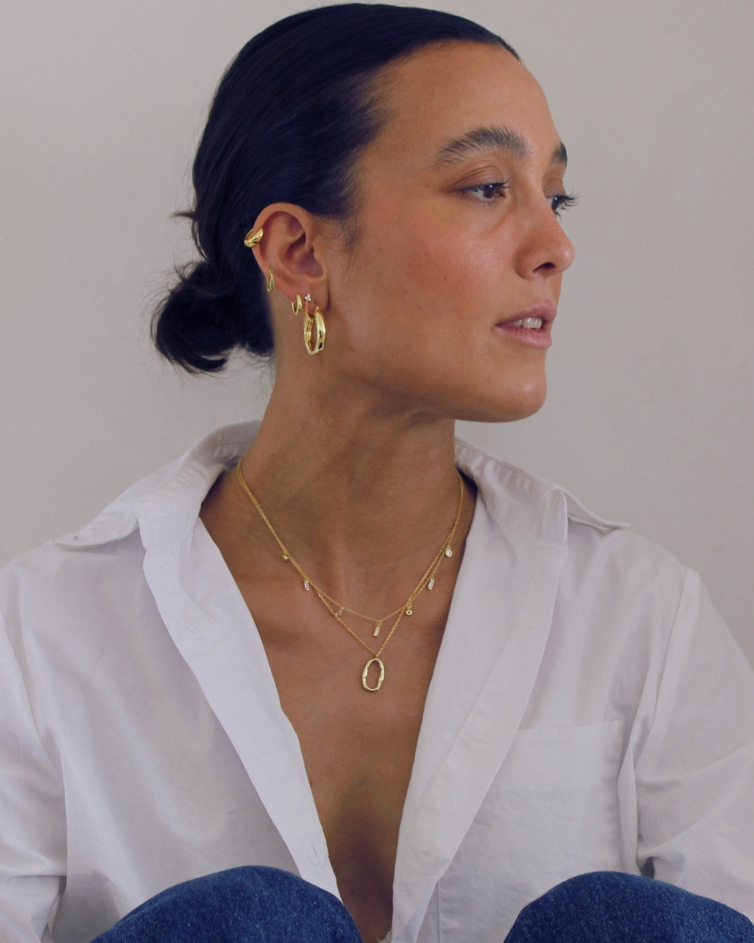 Woman wearing gold jewelry against a plain background
