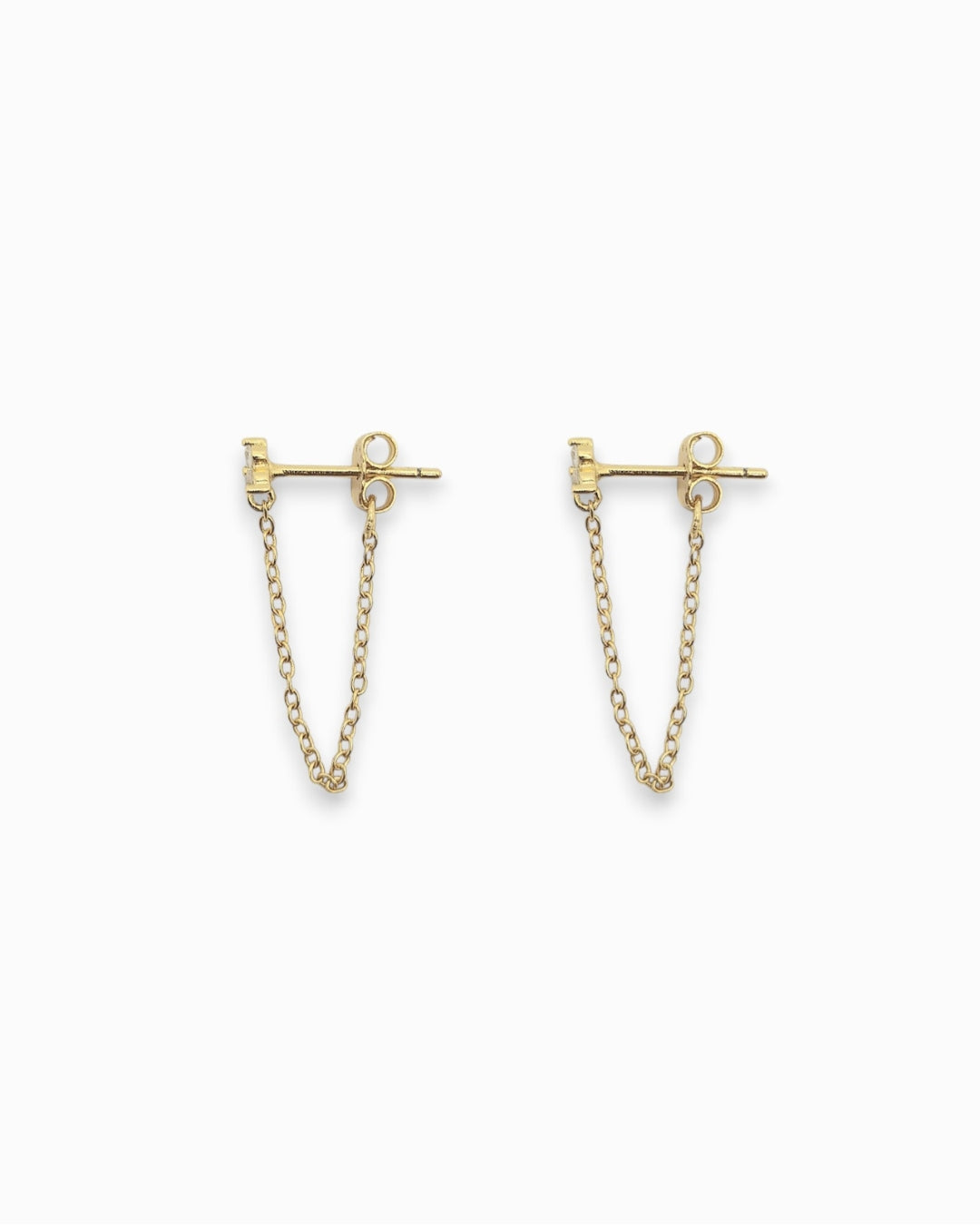 Gold earrings with chain extensions flat lay on a white background