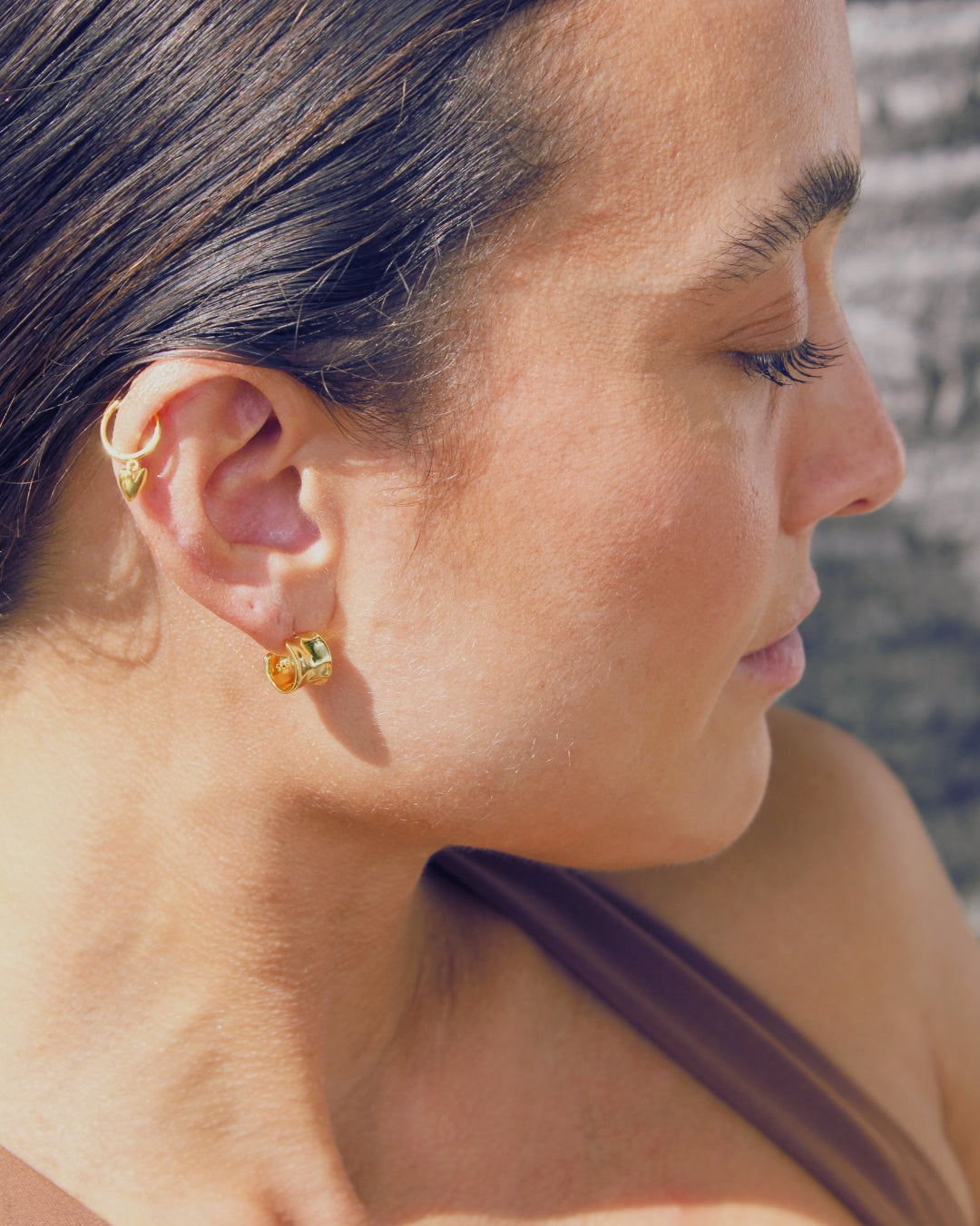Close-up of a woman wearing gold earrings with a blurred background