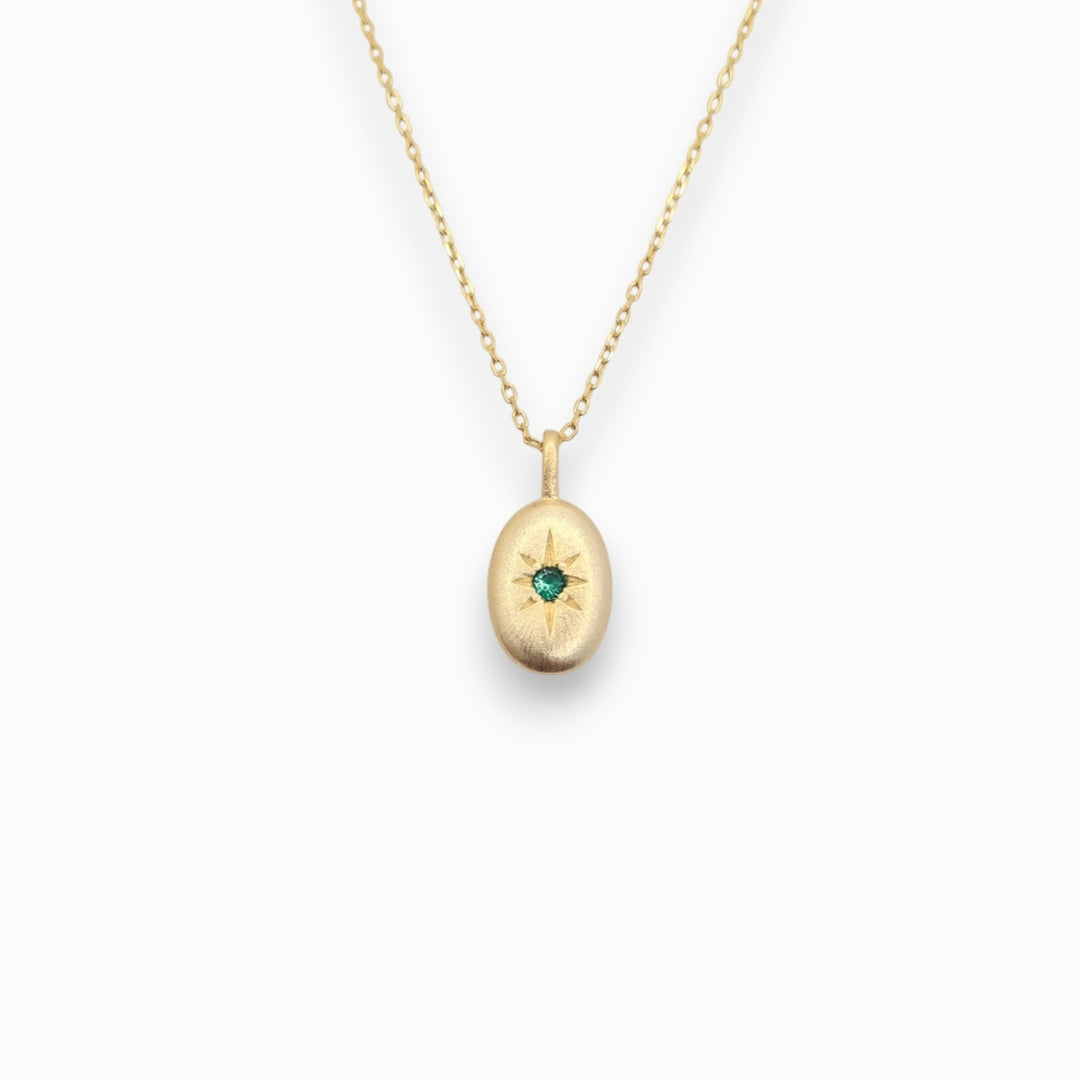 Gold necklace with a pendant featuring a green gemstone on a white background