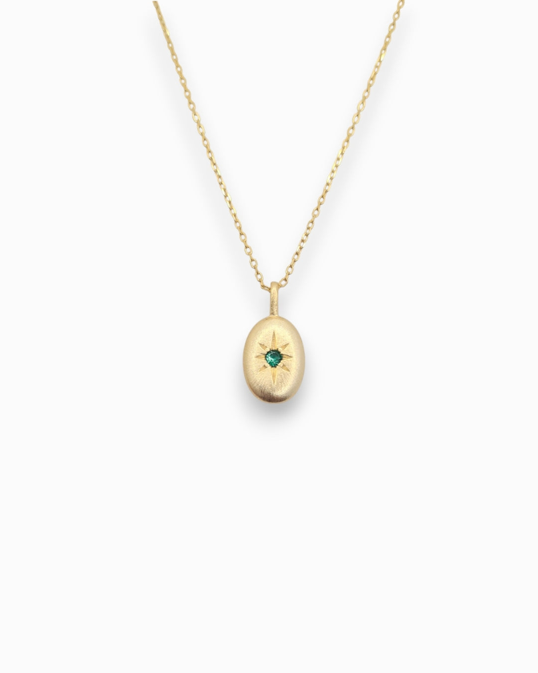 Gold necklace with a pendant featuring a green gemstone on a white background