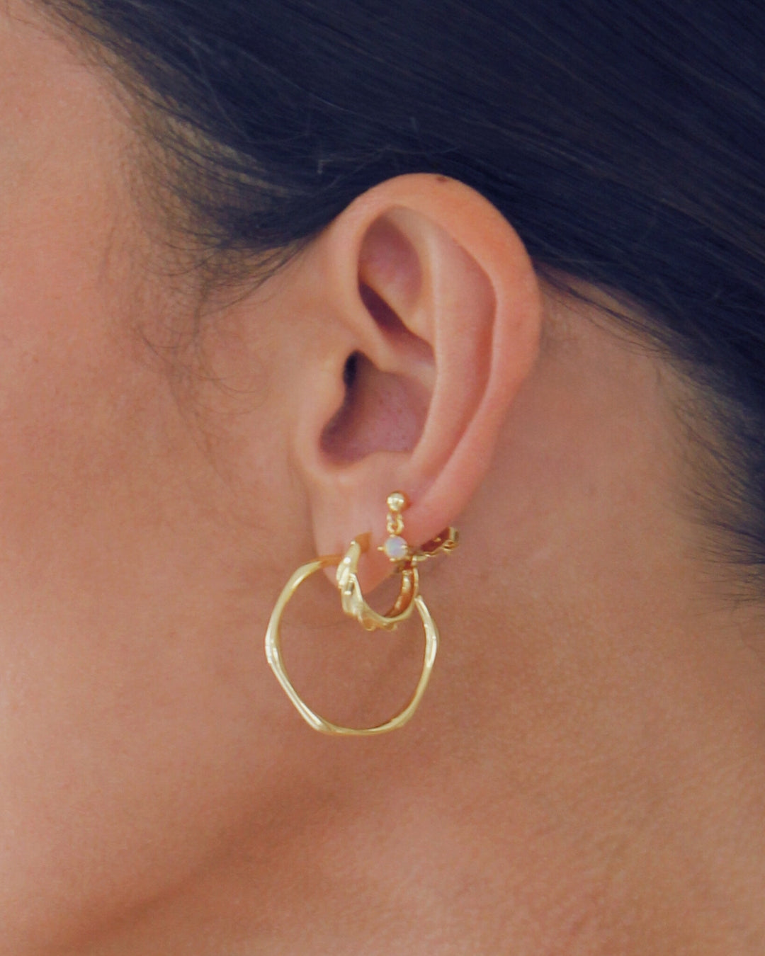 Large 18 carat gold plated hoop earrings worn by a person with dark hair.