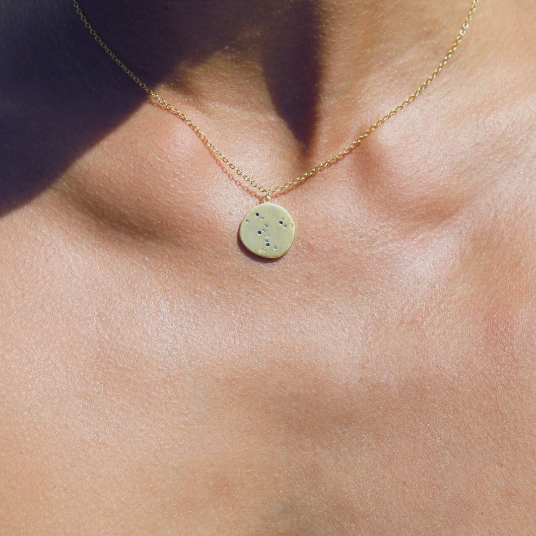 Necklace with a round pendant with small blue gems on a woman's neck