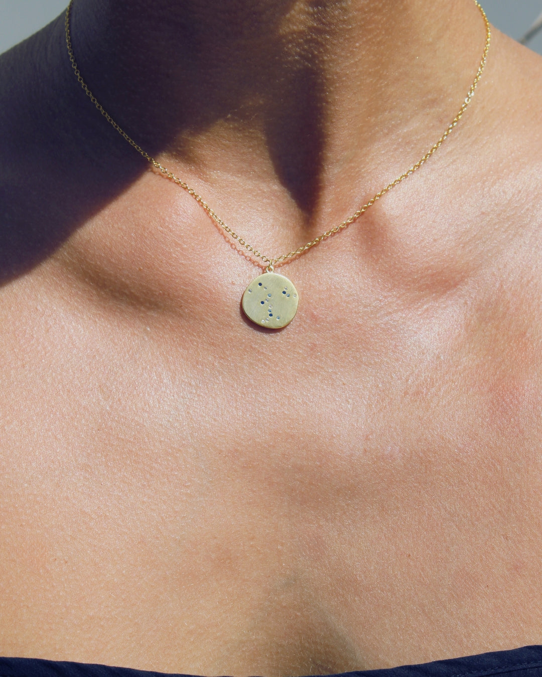Necklace with a round pendant with small blue gems on a woman's neck