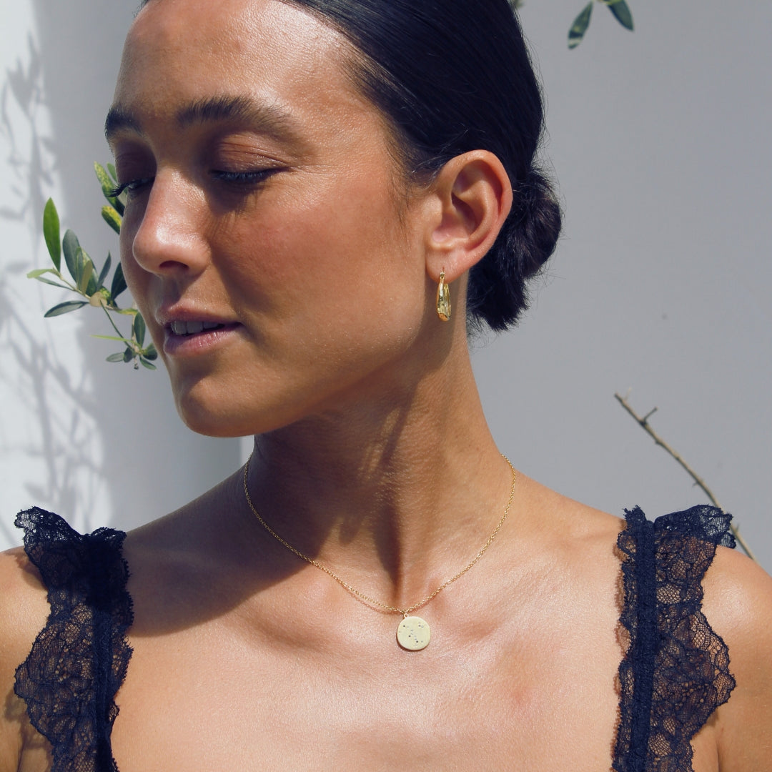 Woman wearing a dark lace top wearing a 18k gold pendant necklace