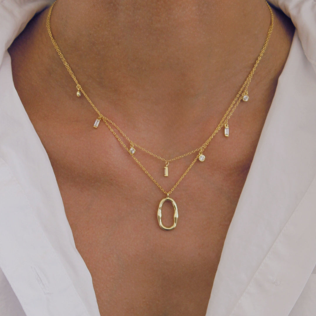 18k Gold necklace with a pendant on a person wearing a white shirt.
