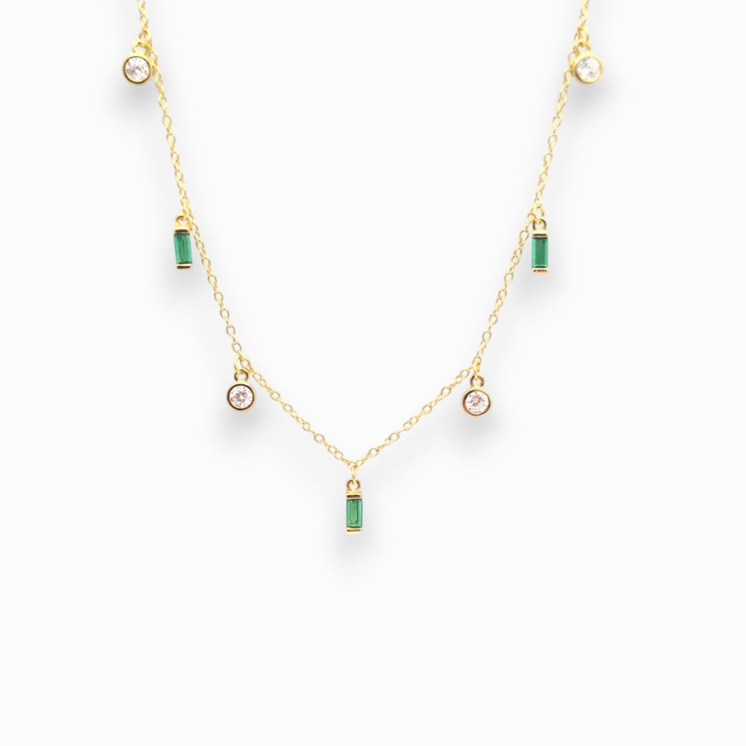 Gold necklace with green and clear zirconia pendant gemstones on a white background