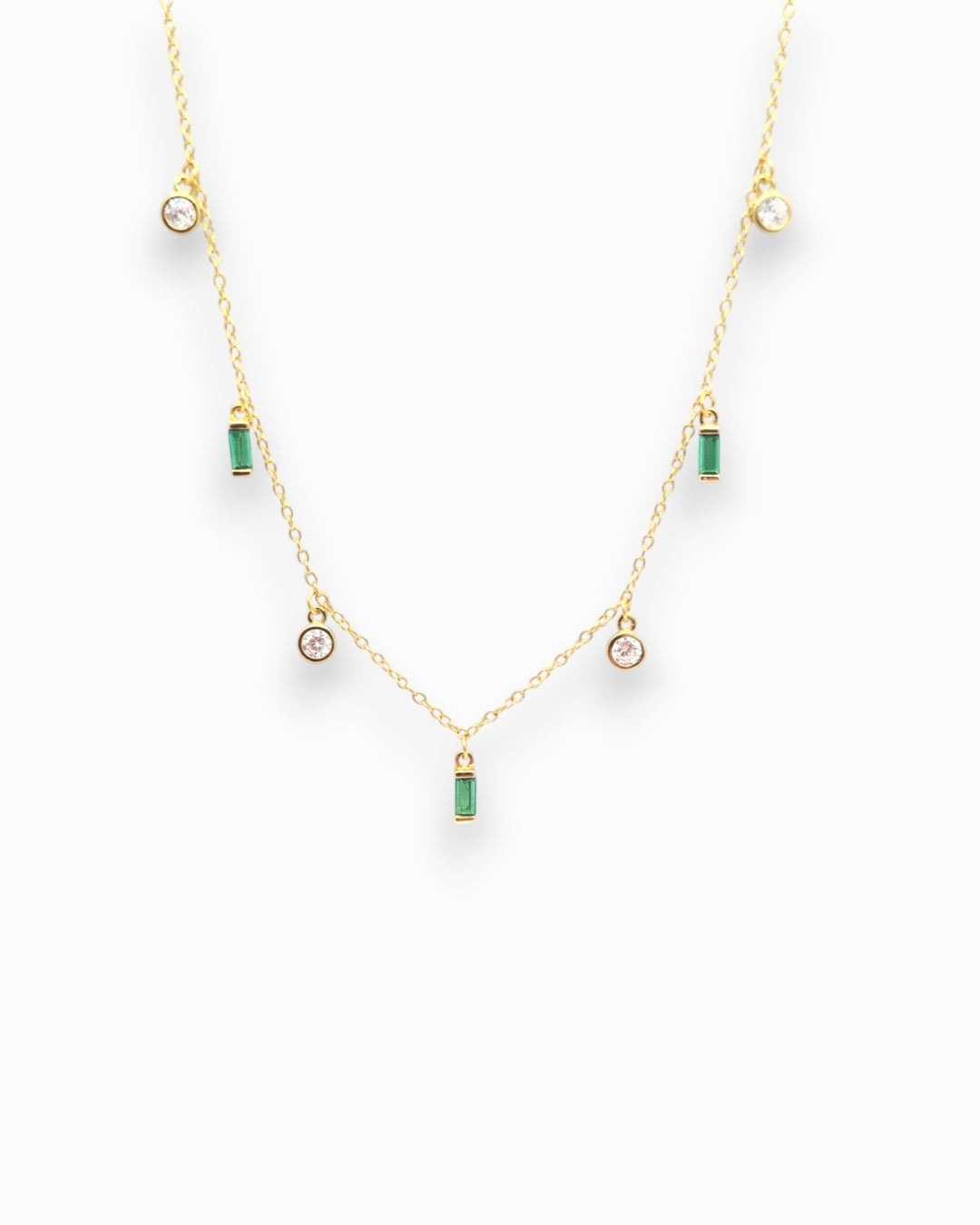 Gold necklace with green and clear zirconia pendant gemstones on a white background