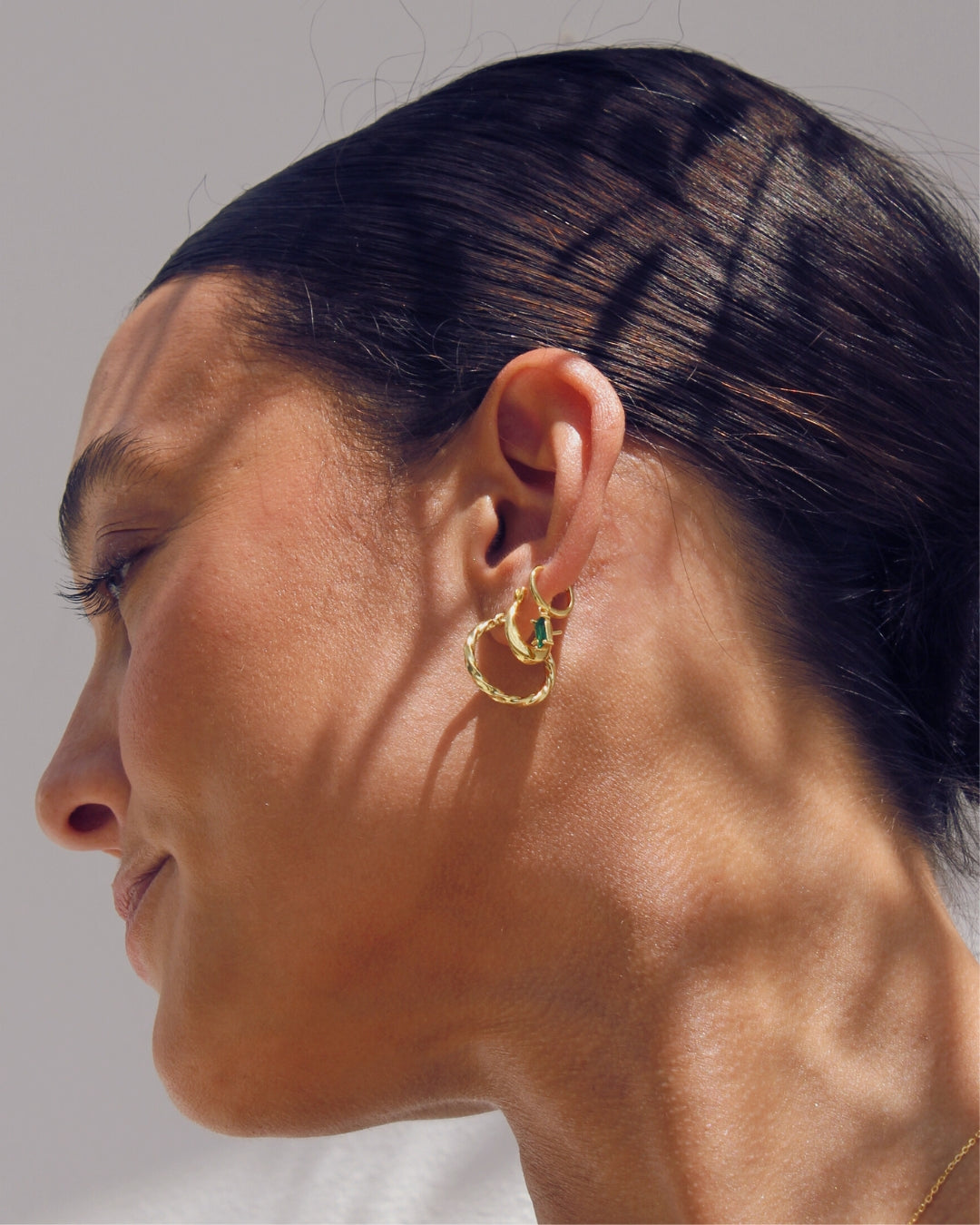 Close-up of a woman wearing gold hoop earrings.