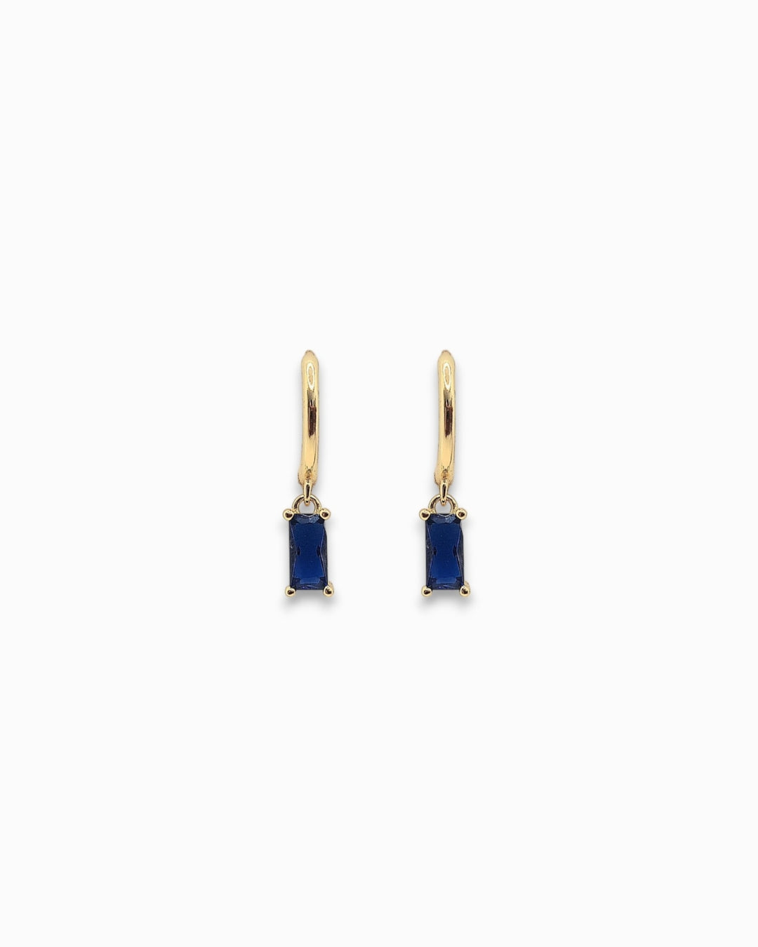 Gold pendant hoop earrings with blue gemstones on a white background