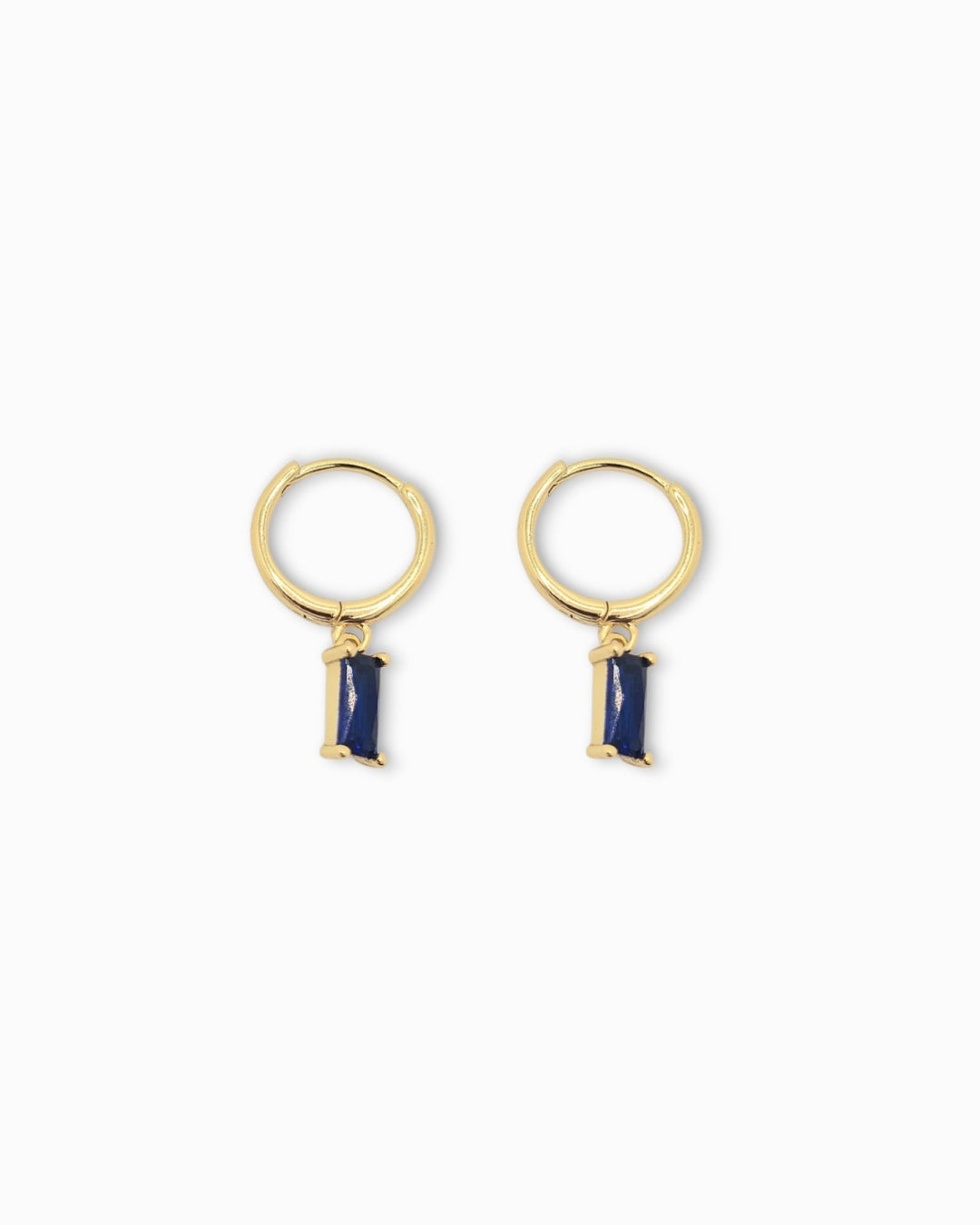 Gold pendant hoop earrings with blue stone drops on a white background