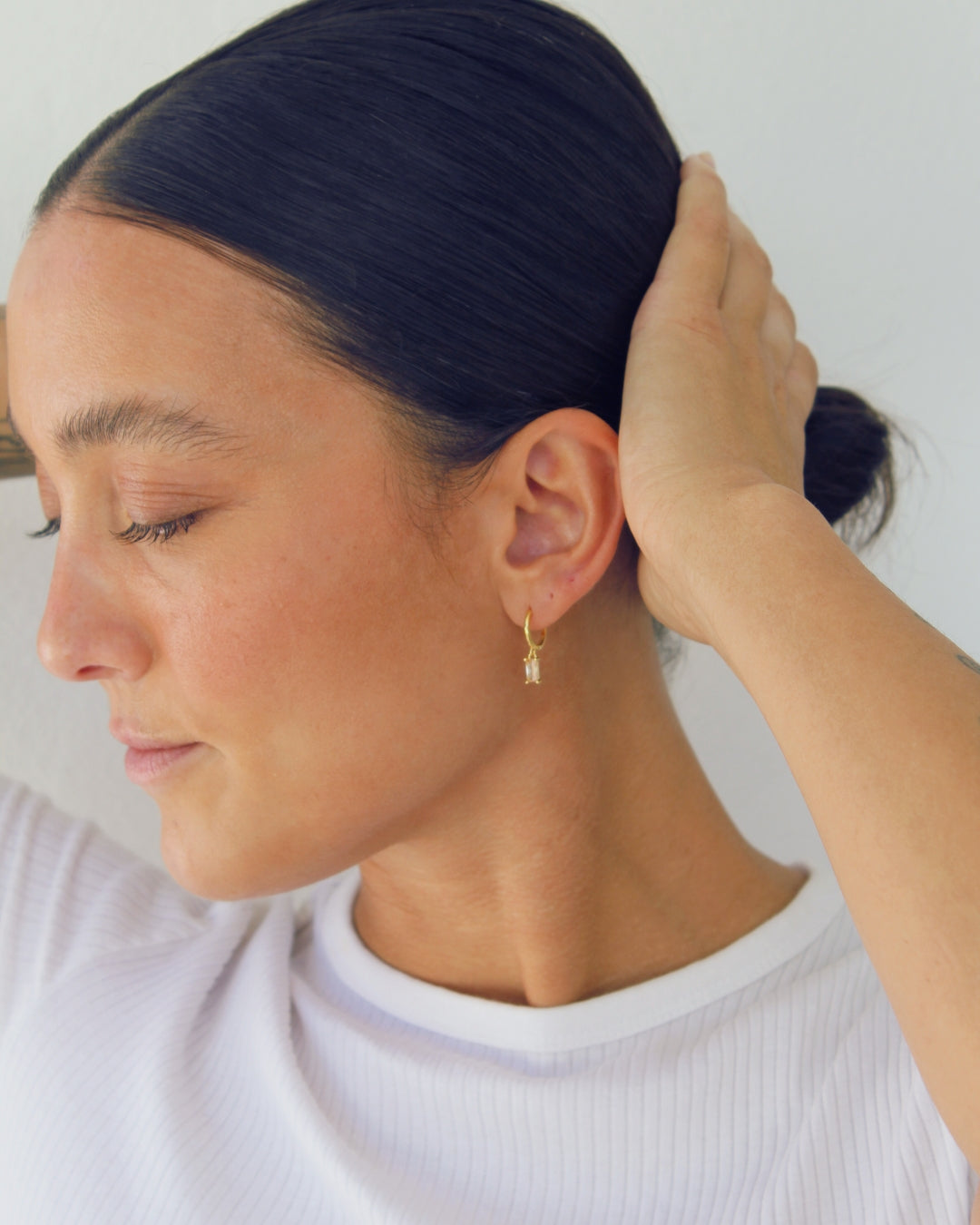 Woman with a bun and gold earring against a white background