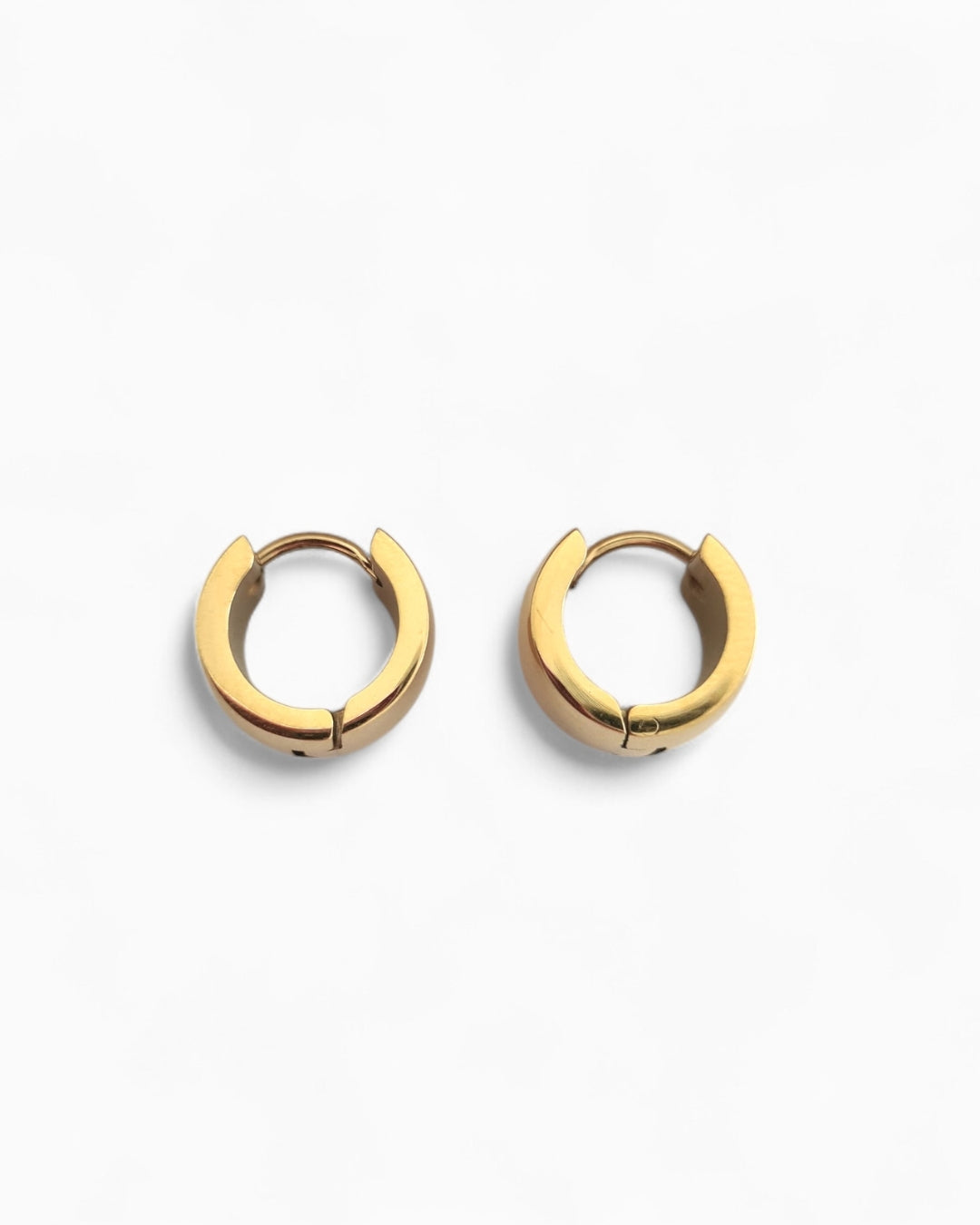 Pair of gold huggie earrings on a white background