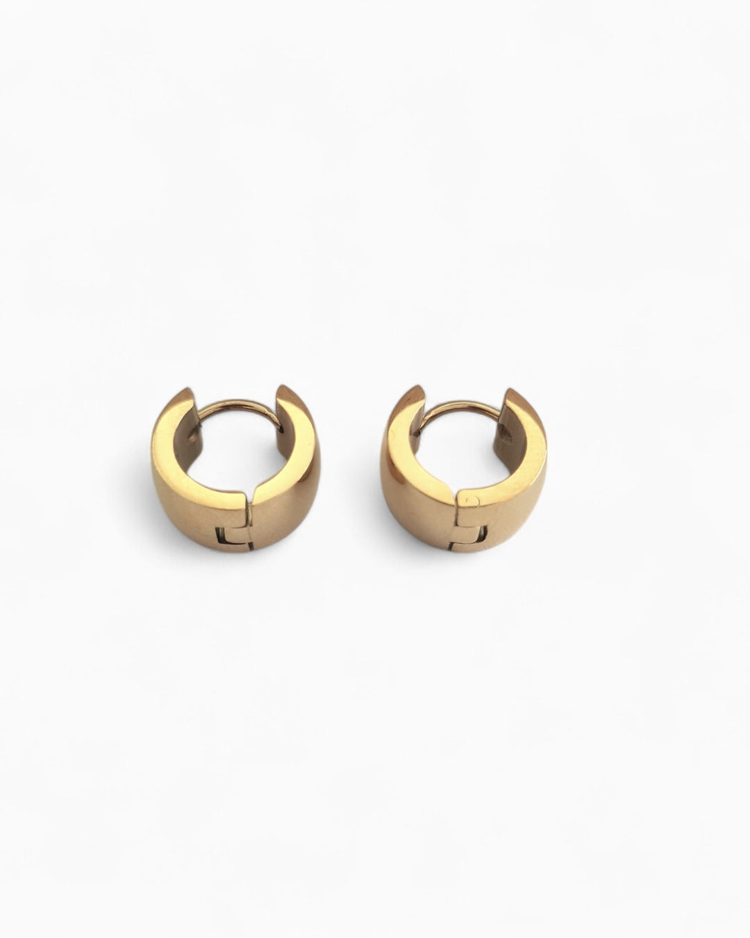 Pair of gold huggie earrings on a white background