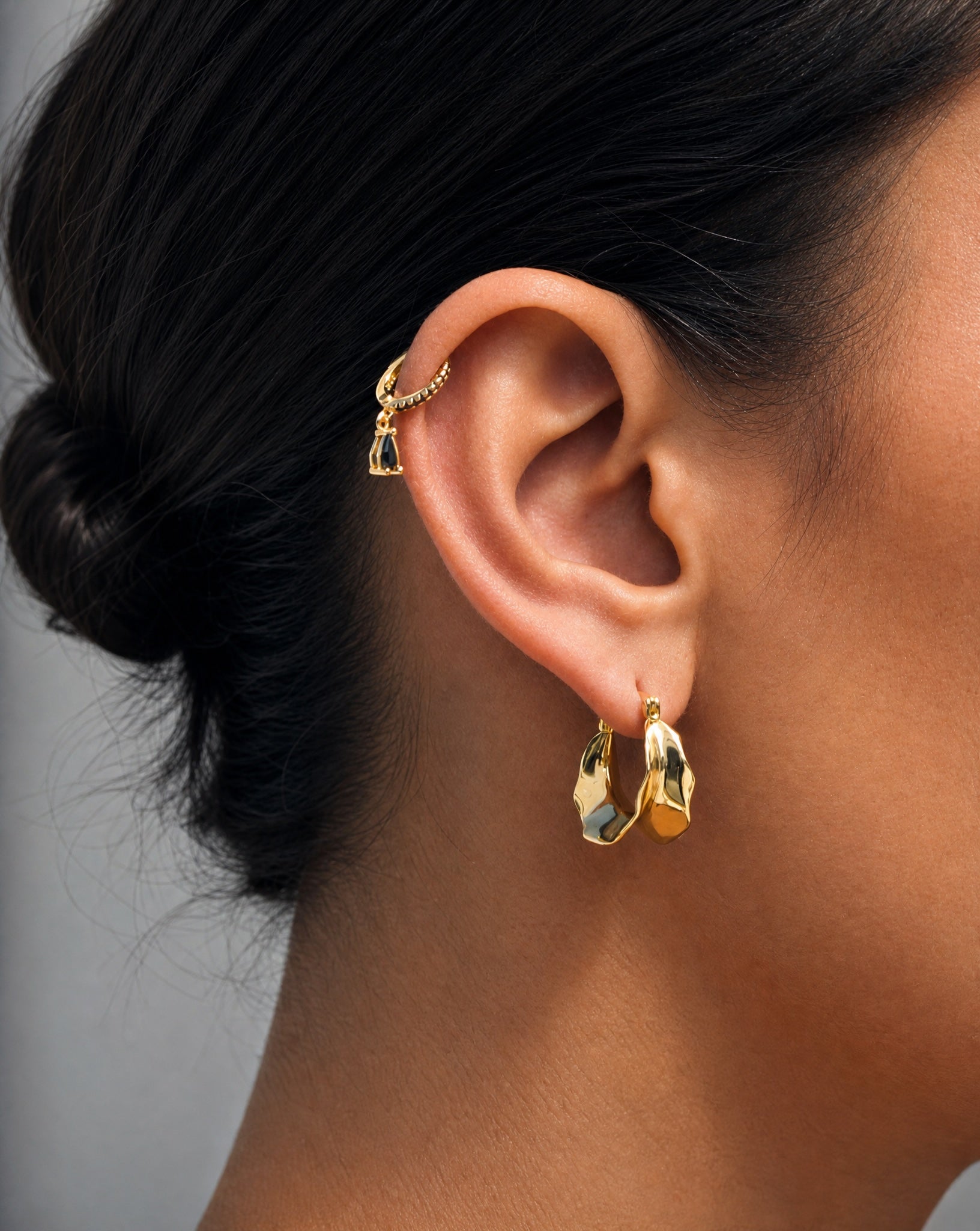 Close-up on the ear wearing the Hunter Rose Bronte 18k gold plated pendant huggie earrings.