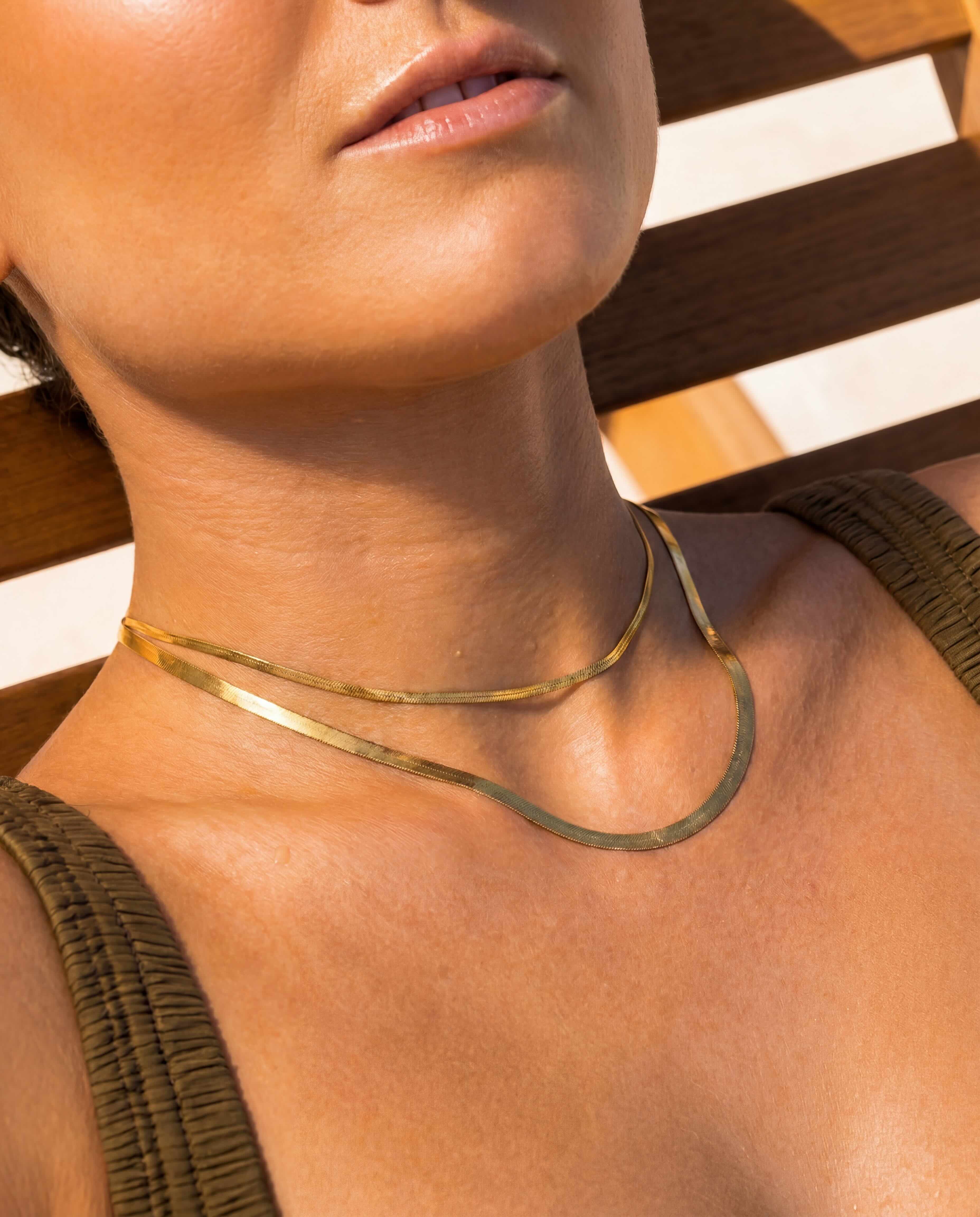 Close-up on a model wearing the layered tarnish-free 18k gold snake chain bundle by Hunter Rose.