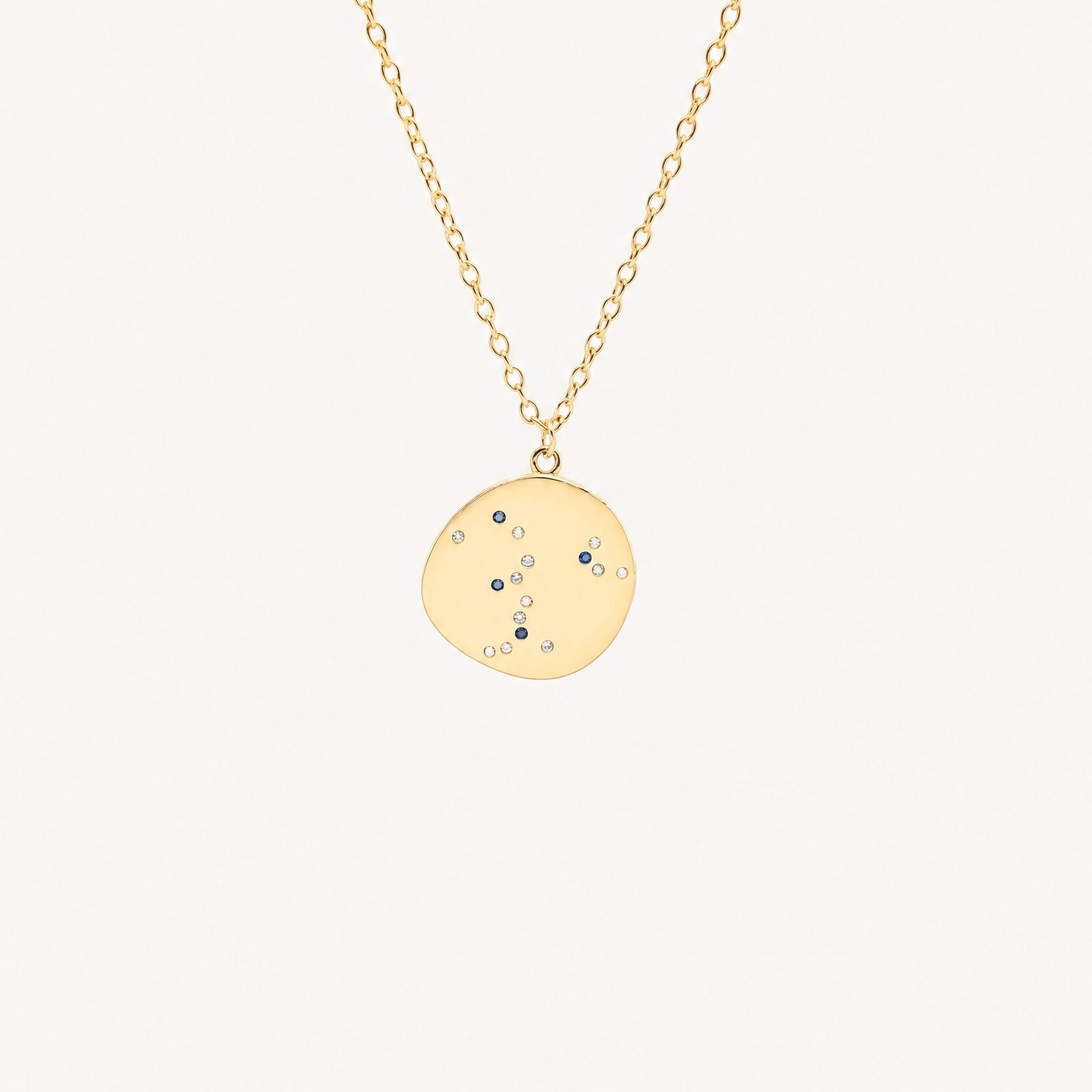 Studio view of the Hunter Rose Luna 18k gold necklace featuring a celestial coin pendant with blue and clear stones.