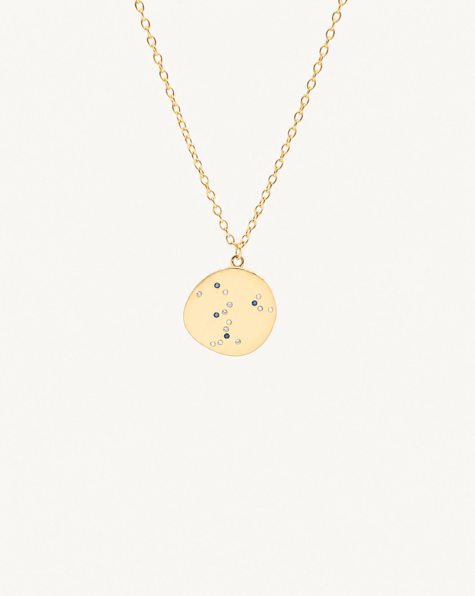 Studio view of the Hunter Rose Luna 18k gold necklace featuring a celestial coin pendant with blue and clear stones.