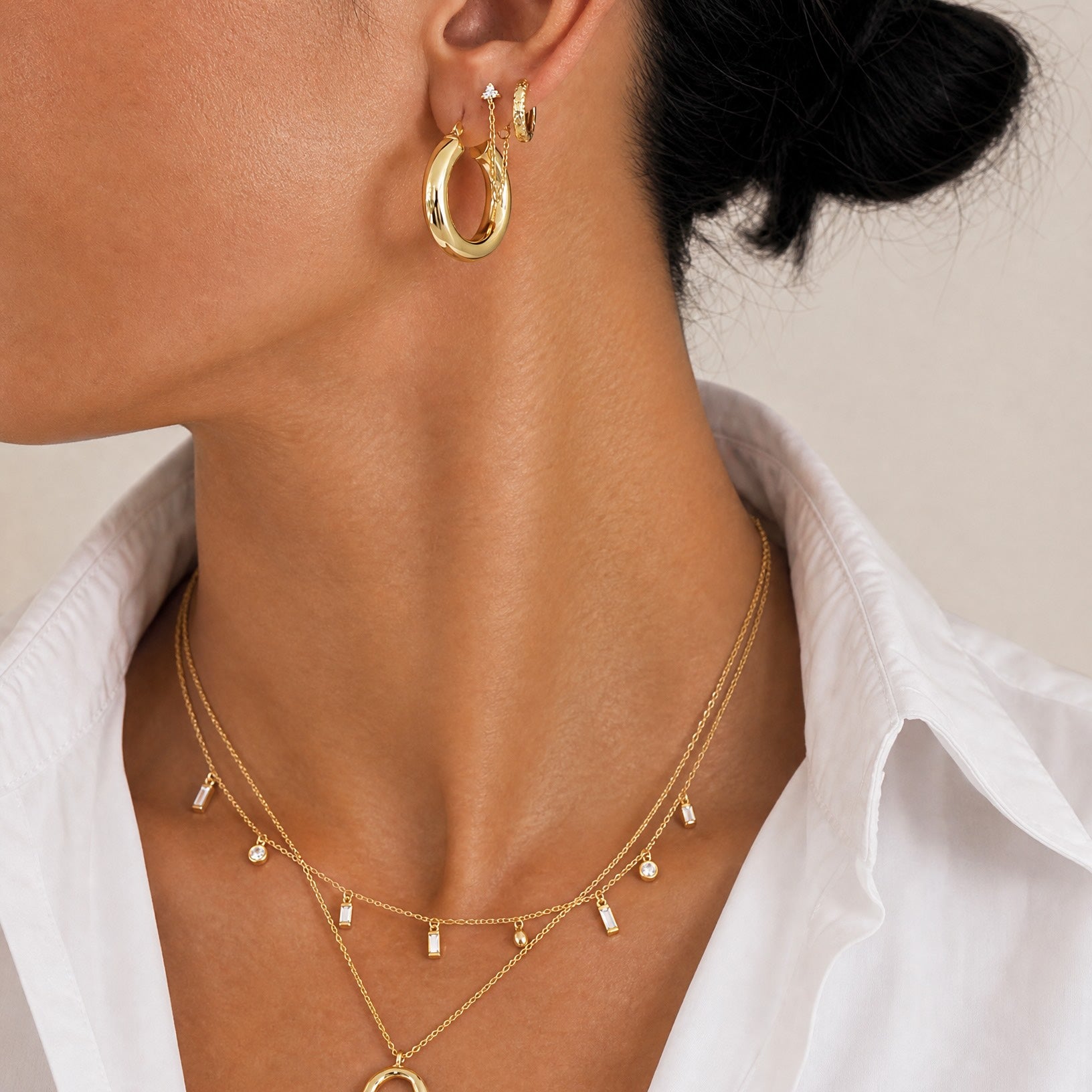 Close-up profile of a model styling the Mae 18k gold plated sterling silver necklace layered with other demi-fine gold jewellery by Hunter Rose.