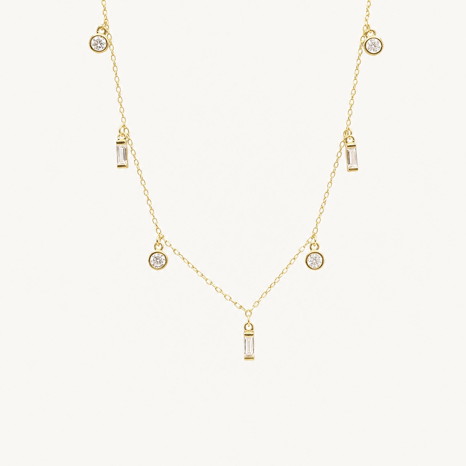 Studio view of the Maisie 18k gold plated necklace featuring round and baguette clear stones by Hunter Rose.