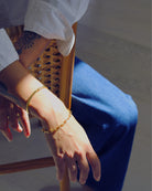 Close-up of a person's wrist wearing gold bracelets with a blurred background.