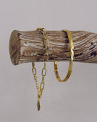 Gold bracelets on a wooden log against a gray background