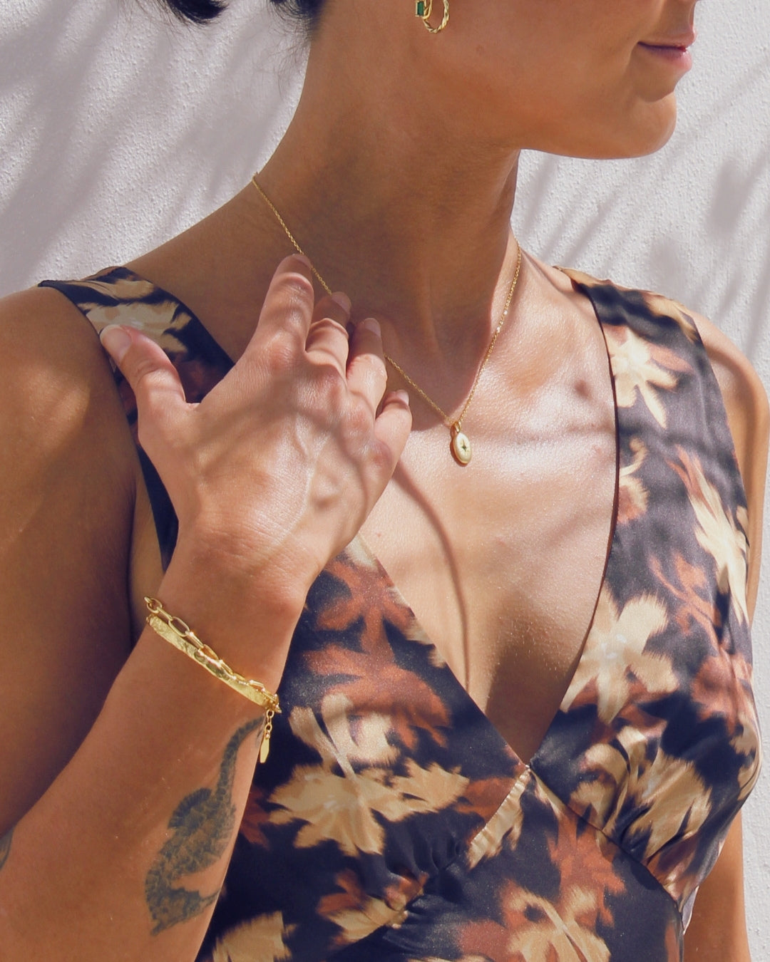 Woman wearing a floral dress with a gold necklace and the Avalon cuff bracelet against a neutral background