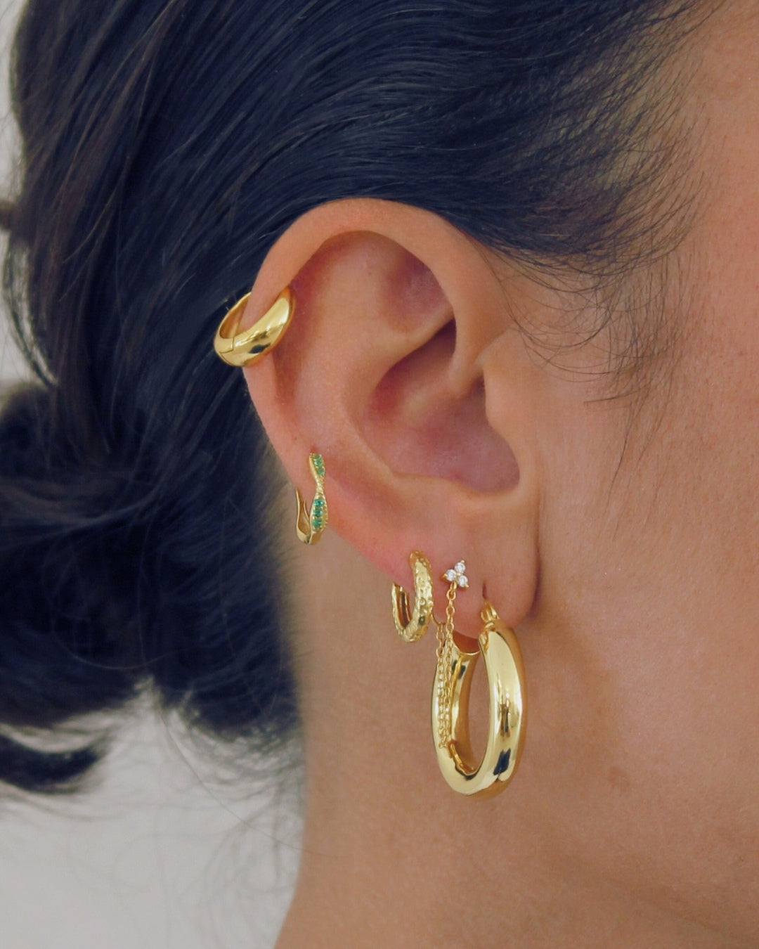 Close-up of an ear wearing a 5 stack of 18k gold earrings