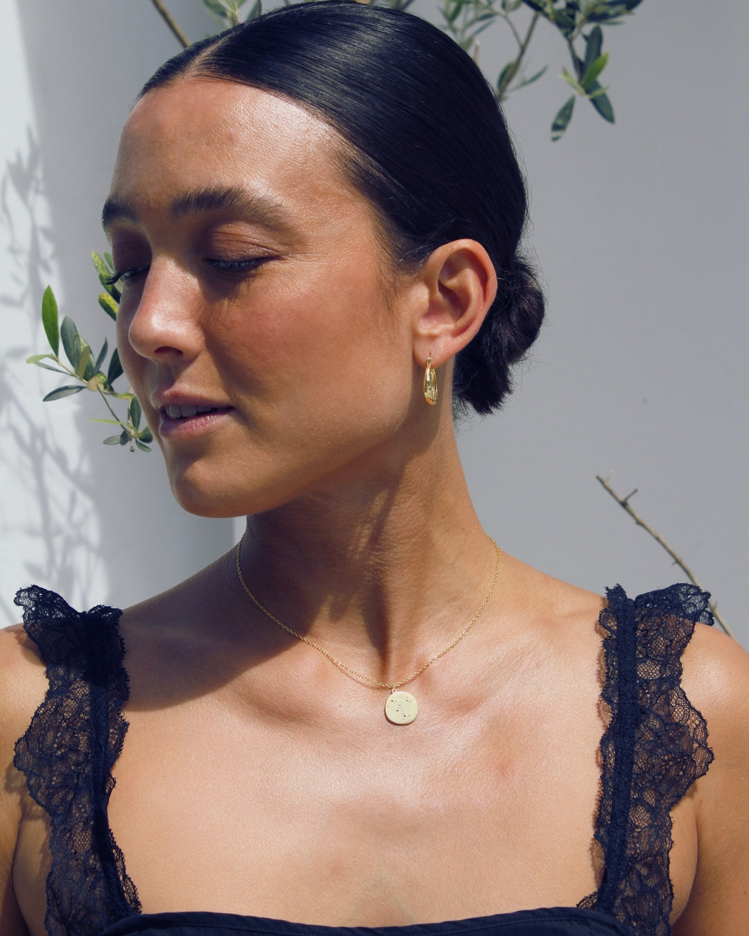 Woman wearing a dark lace top wearing a 18k gold pendant necklace