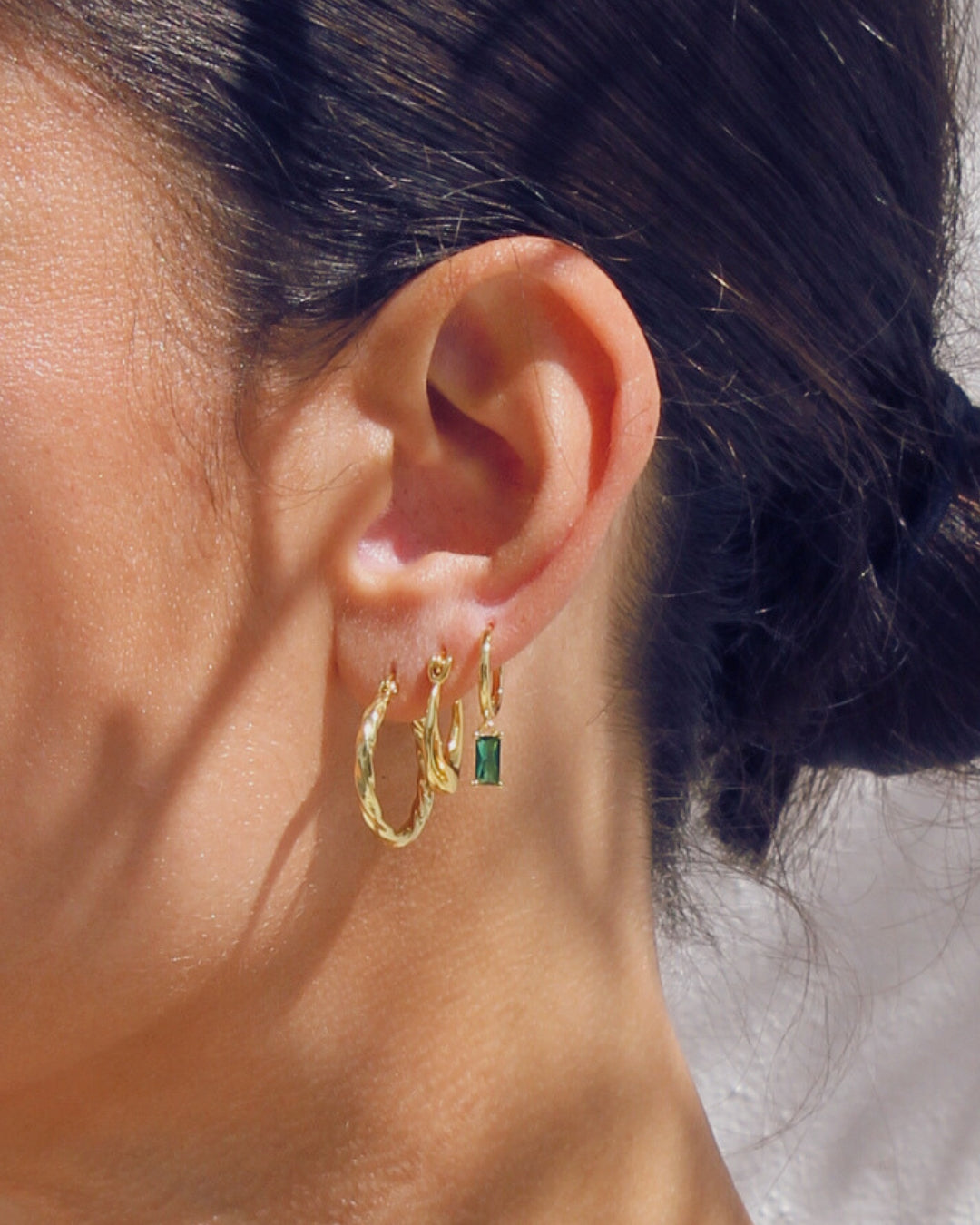 Close-up of an ear wearing 18 carat gold hoop earrings