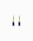 Gold pendant hoop earrings with blue gemstones on a white background
