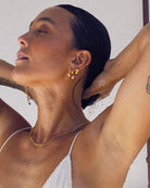 Woman wearing waterproof gold jewellery in a white bikini in an outdoor shower