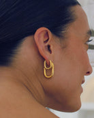Close-up of a person wearing gold hoop earrings with a blurred background