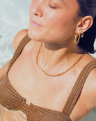 Woman wearing a brown bikini and waterproof 18 k gold jewellery in a pool