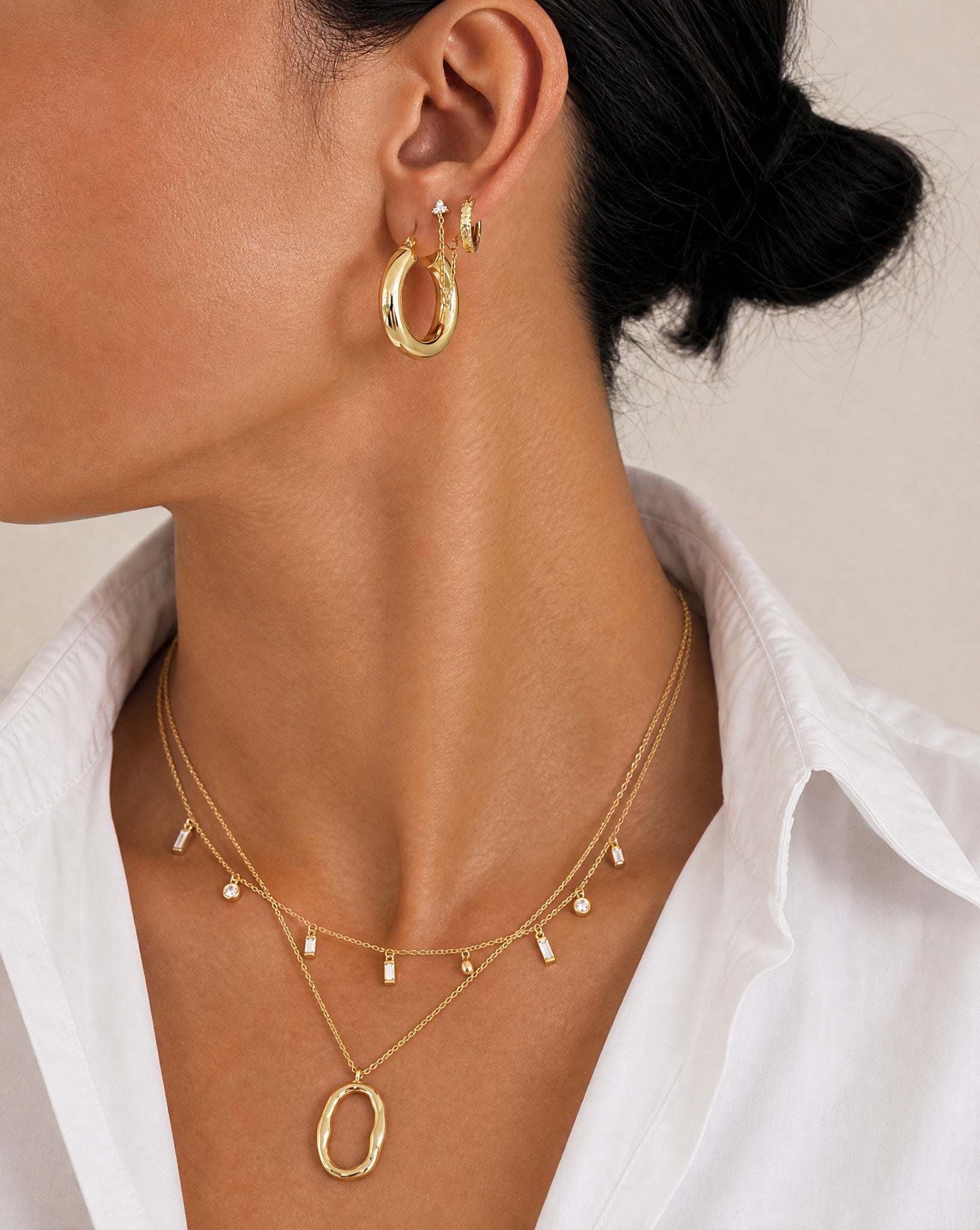 Close-up profile of a model styling the Mae 18k gold plated sterling silver necklace layered with other demi-fine gold jewellery by Hunter Rose.