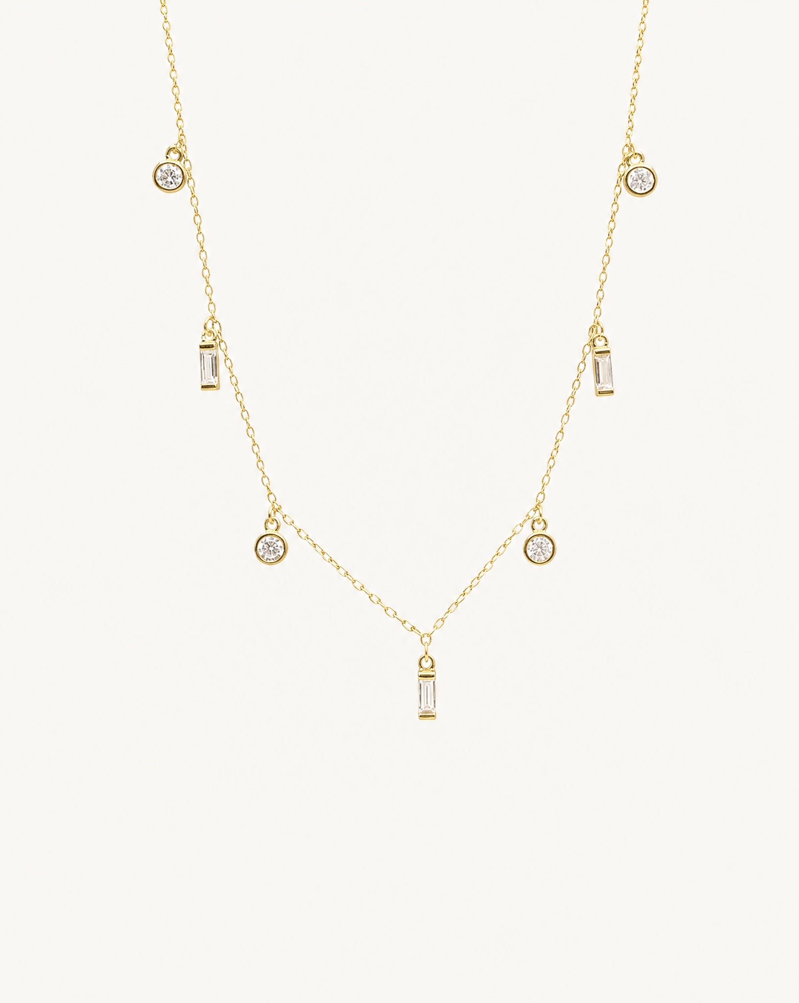Studio view of the Maisie 18k gold plated necklace featuring round and baguette clear stones by Hunter Rose.